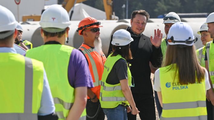 Elon Musk, Tesla-Chef, lässt sich mit Arbeitern am Rande eines Pressetermins auf dem Gelände der Tesla Gigafactory fotografieren. (Quelle: dpa/Patrick Pleul)