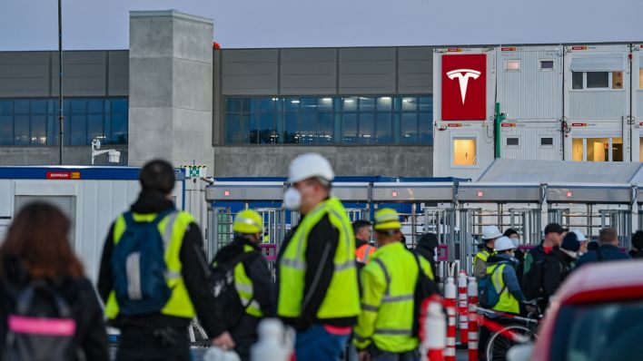 Arbeiter warten am frühen Morgen an einem Eingang zur Baustelle für die Tesla-Autofabrik. (Quelle: dpa/Patrick Pleul)