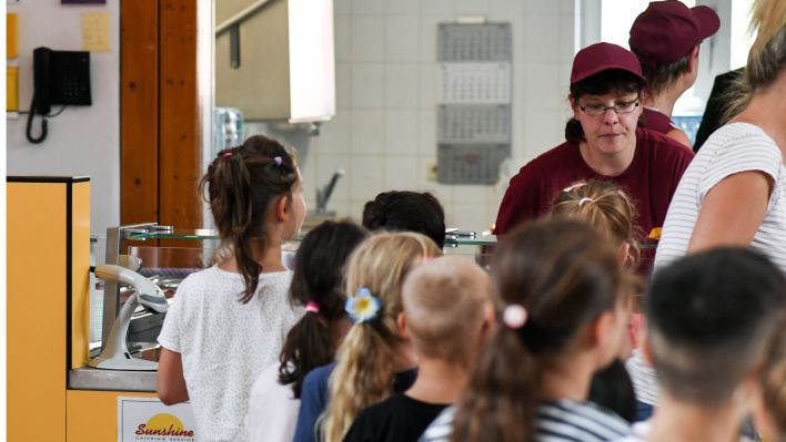 Schüler stehen vor dem Mittagessen in der Mensa in der Grundschule an der Wuhlheide in der Schlange vor der Essensausgabe. (Quelle: dpa/ Jens Kalaene)