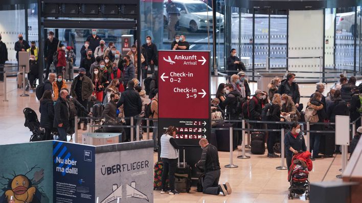 Am Flughafen BER stehen Reisende in einer Warteschlange an einem Check-In-Schalter. (Quelle: dpa/J. Carstensen)