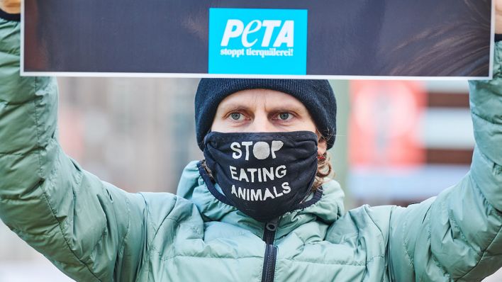"Stop eating animals" steht auf dem Mund-Nasen-Schutz, den ein Demonstrant trägt. (Quelle: dpa/Annette Riedl)