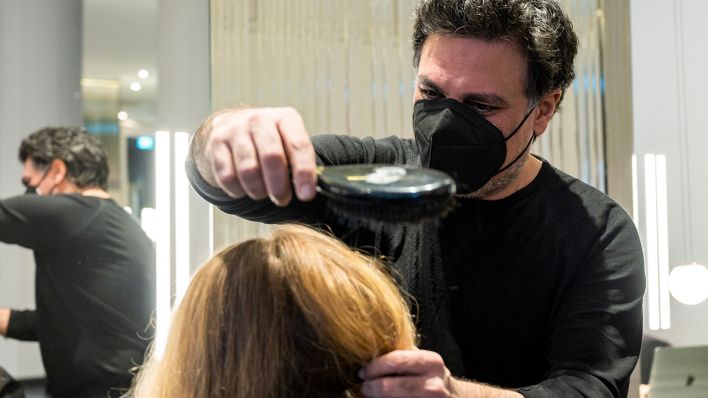 Shan Rahimkhan, Berliner Friseur, bürstet einer Kundin in seinem Friseursalon die Haare. (Quelle: dpa/Christophe Gateau)