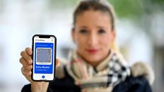 Symbolbild: Frau zeigt App CovPass auf Smartphone mit digitalem europäischen Impfzertifikat. (Quelle: imago images/M. Weber)
