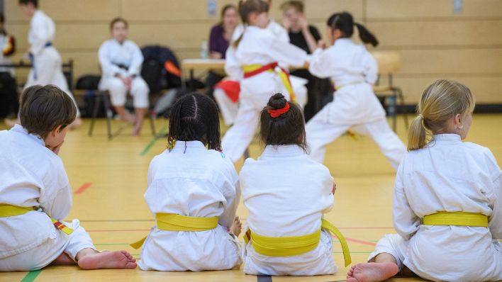 Drei Mädchen und ein Junge beobachten ihre Konkurrentinnen bei einem Karate-Wettkampf für Kinder in Berlin. (Quelle: dpa/Hans Wiedl)