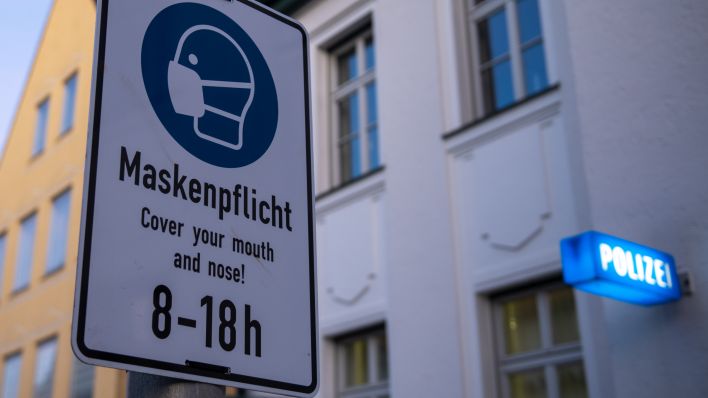 Vor der Polizeiinspektion weist ein Schild auf die Maskenpflicht von 8 bis 18 Uhr hin. (Quelle: Stefan Puchner/dpa)