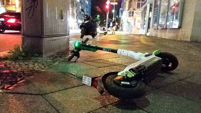 Symbolbild: E-Roller liegt nachts auf der Straße auf einem Gehweg. (Quelle: dpa/W. Steinberg)
