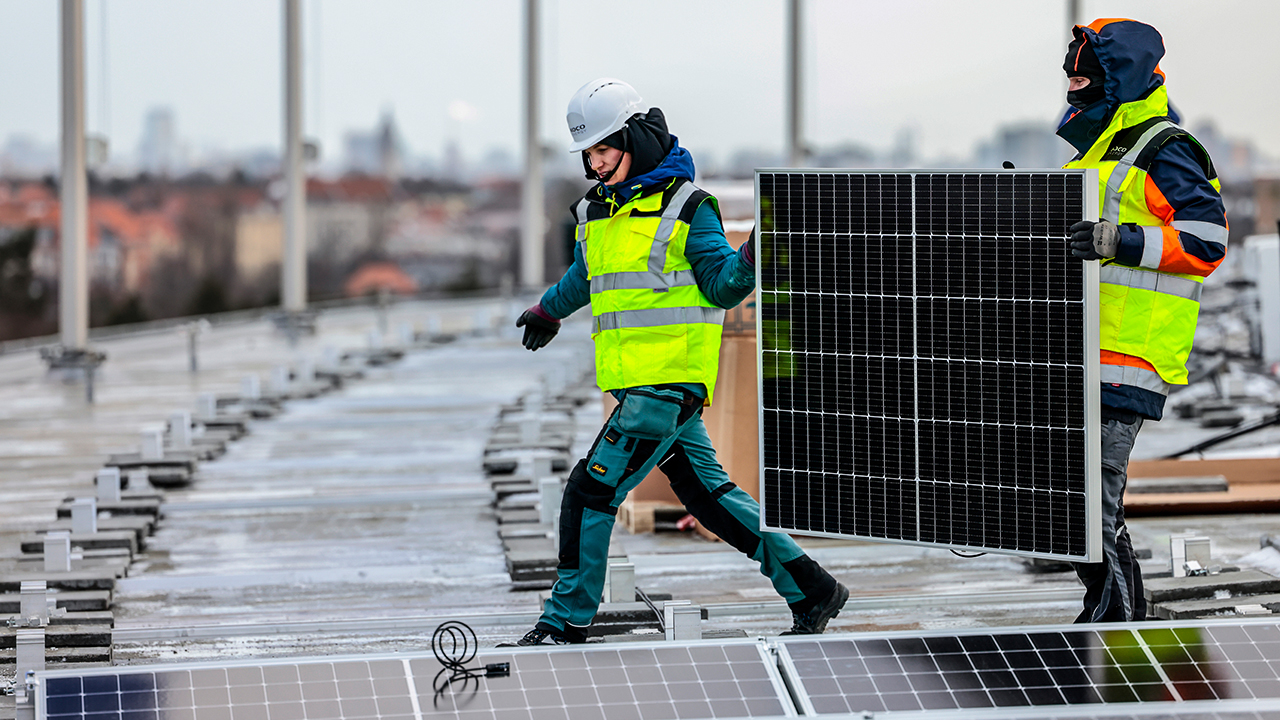 Arbeiter:innen montieren Solarmodule einer neuen Photovoltaik-Anlage auf dem Dach des Olympiastadions (Bild: dpa/Michael Hanschke)