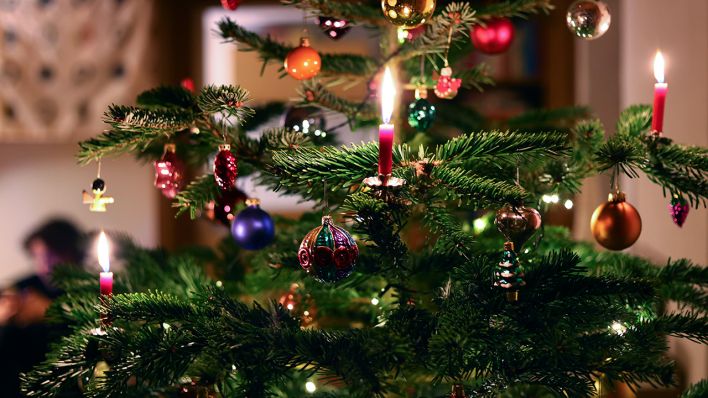 Symbolbild: Kerzen brennen in einem Wohnzimmer an einem festlich geschmückten Weihnachtsbaum (Bild: dpa/Karl-Josef Hildenbrand)