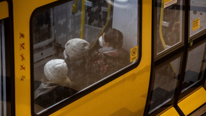 Fahrgäste sitzen mit FFP2-Masken in einer U-Bahn. (Quelle: Paul Zinken/dpa)