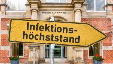Ein gelbes, zerkratztes Hinweisschild mit der Aufschrift "Infektionshöchststand" vor dem Robert-Koch-Institut. (Torsten Sukrow/SULUPRESS.DE)
