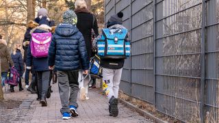 Mehrere Kinder und Eltern laufen zur Berliner Grunewald-Grundschule (Bild: imago images/Stefan Zeitz)