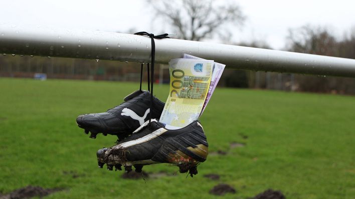 Fußballschuhe sind an einer Stange festgeschnürt. In ihnen stecken Geldcheine (Foto: imago images / Hanno Bode)
