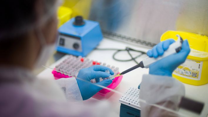 Ein Mitarbeiter hält in einem Coronatest-Labor der Limbach Gruppe PCR-Teströhrchen in den Händen. (Quelle: imago images/Nathan Laine)