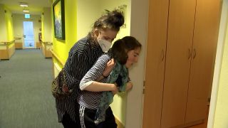 Eine Heilerziehungspflegerin hilft einer Frau mit Behinderung aus dem Rollstuhl in ihr Zimmer. (Bild: rbb)