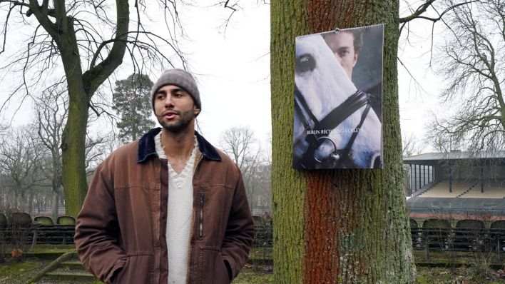 Benjamin Patch steht mit Händen in der Jackentasche neben Baum mit Fotokalender (Quelle: rbb/Lynn Kraemer)