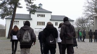 Schüler stehen vor dem Eingang der Gendenkstätte Sachsenhausen.