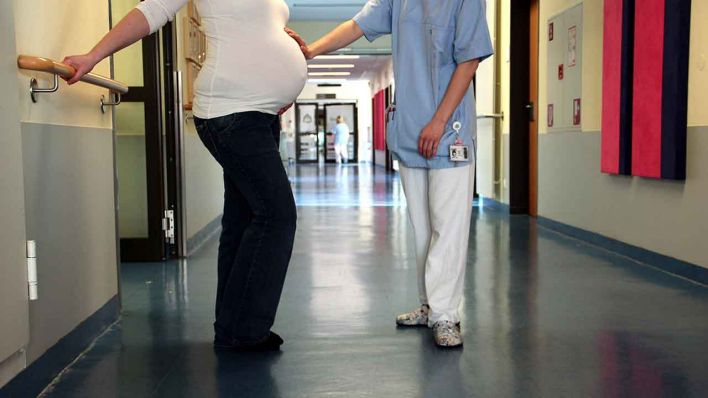 ILLUSTRATION - Eine schwangere Frau und eine Hebamme stehen am 22.03.2012 auf dem Flur des Kreissaals (Quelle: dpa/Mascha Brichta)