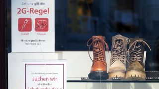 Ein Schild mit der Aufschrift „Bei uns gilt die 2G-Regel Geimpft Genesen“ hängt im Schaufenster eines Schuhgeschäftes in der Brandenburger Straße. (Quelle: dpa/Sören Stache)