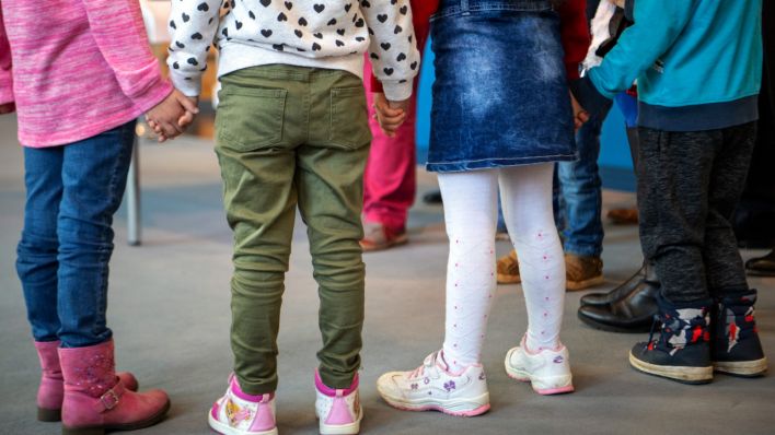Kinder im Kindergartenalter stehen nebeneinander und halten sich an den Händen. (Quelle: dpa/Monika Skolimowska)
