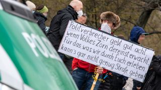 Ein Mann zwischen Querdenker-Demonstranten hält in Berlin am 13.04.2021 ein Plakat. (Quelle: dpa/Andreas Gora)