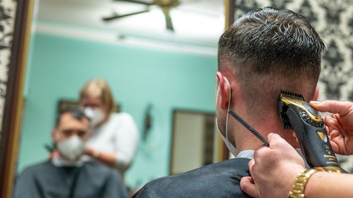 Ein Friseurin rasiert die Haare eines Kunden (Quelle: dpa/Armin Weigel)
