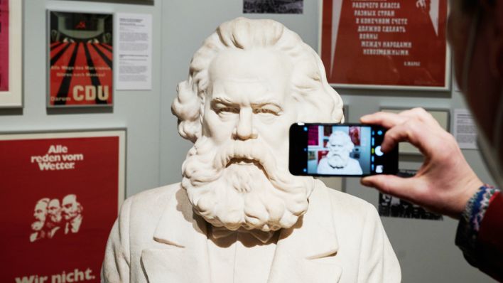 Eine Person fotografiert die Büste von Karl Marx von Constantin Baraschi, 1953 in der Ausstellung "Karl Marx und der Kapitalismus" im Deutschen Historischem Museum. (Quelle: dpa/Annette Riedl)