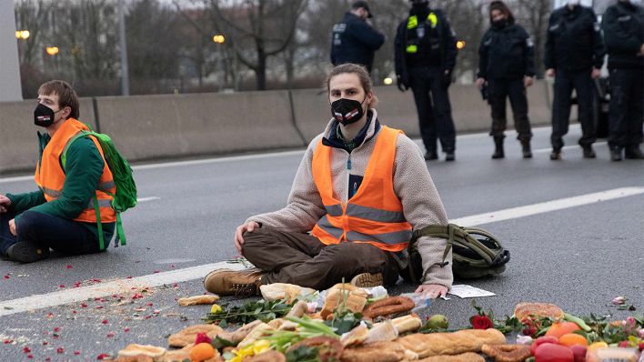 Ein Klimaaktivist der Gruppe „Aufstand der letzten Generation" sitzt auf der A100 (Bild: dpa/Carsten Koall)