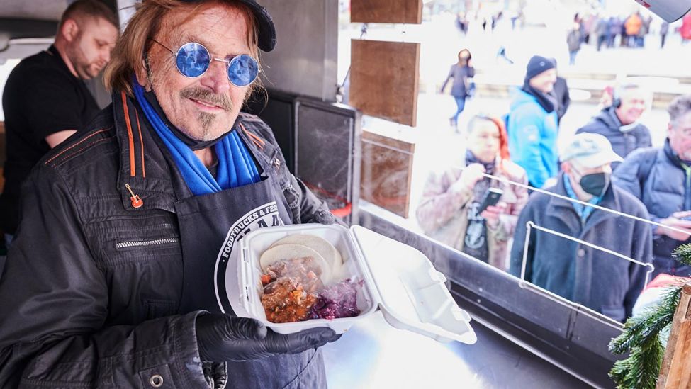 Frank Zander steht im Caritas-Foodtruck und verteilt warme Mahlzeiten an Obdachlose und bedürftige Menschen auf dem Alexanderplatz. (Quelle: dpa/Annette Riedl)