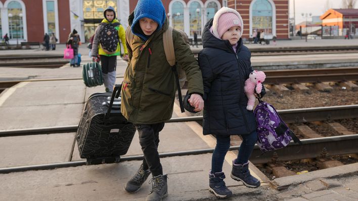 Zwei Kinder überqueren in Kramatorsk in der Region Donezk in der Ostukraine Hand in Hand die Gleisen, um einen Zug nach Kiew zu nehmen. (Quelle: dpa/V. Ghirda)