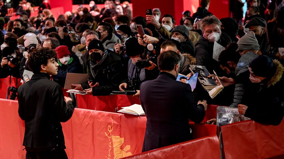 Regisseur François Ozon (r) und Schauspieler Khalil Gharbia geben Autogramme bei der Eröffnungsveranstaltung der 72. Berlinale Internationalen Filmfestspiele. (Quelle: dpa/B. Pedersen)