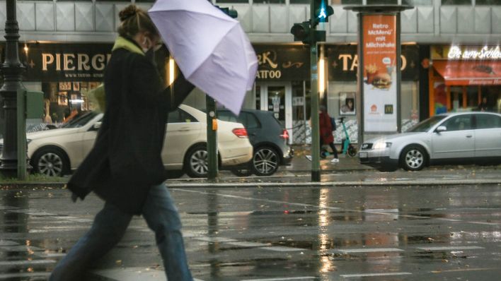 Frau mit Regenschirm im Sturm und im Regen auf der Straße (Quelle: www.imago-images.de/Rolf Kremming)