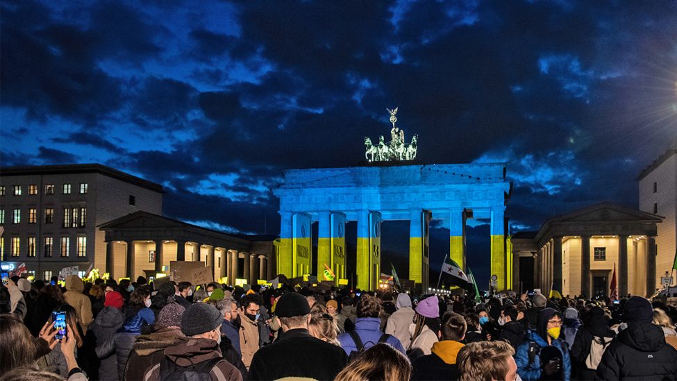 Das Brandenburger Tor wird am Abend des 24.02.2022 bei einer Solidaritäts-Demonstration für die Ukraine, nach dem russischen Einmarsch in das Land, in den Farben der Ukraine angeleuchtet. (Quelle: dpa/Paul Zinken)