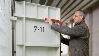 Symbolbild: Ein Mann steht an einer massiven Bunker-Stahltür. (Quelle: dpa/O. Dietze)