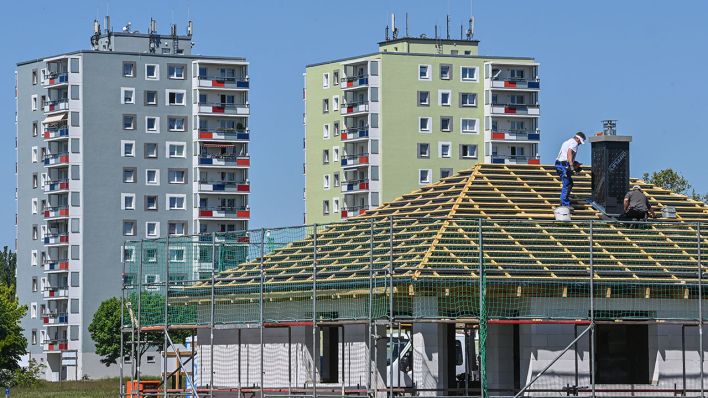 Ein Einfamilienhaus wird in Sichtweite von sanierten Hochhäusern aus DDR-Zeiten gebaut. (Quelle: dpa/Patrick Pleul)