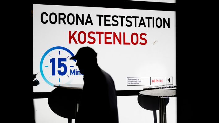Ein Passant läuft im Berliner Bezirk Wilmersdorf an einer Corona-Teststation mit der Aufschrift "kostenlos" vorbei. (Quelle: dpa/Christoph Soeder)