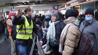 Der freiwillige Helfer Marcel, ein Ingenieur in Elternzeit, sagt am Hauptbahnhof gerade angekommenen Flüchtlingen, wie sie ins LAF kommen, oder wie sie ein Bahnfahrschein für die Weiterfahrt bekommen. (Quelle: dpa/Jörg Carstensen)