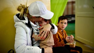 Eine Frau und zwei Kinder, die vor dem Krieg und dem russischen Angriff aus der Ukraine geflüchtet sind, sitzen in einer Unterkunft für Flüchtende. (Quelle: dpa/Marton Monus)