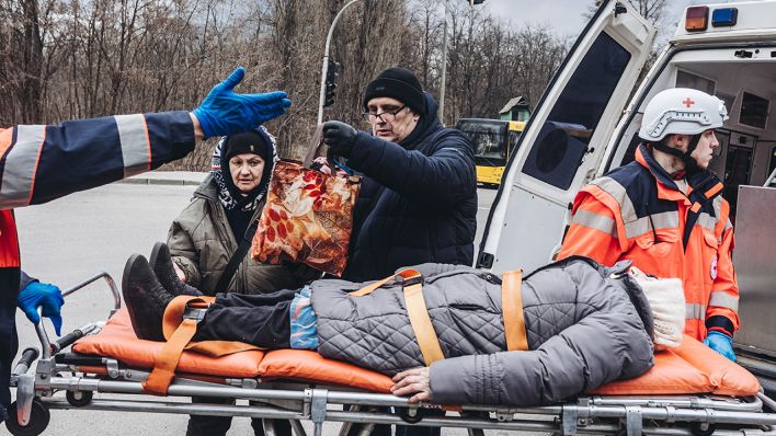 Eine ältere Frau liegt auf einer Trage in Irpin, Ukraine, vor einem Krankenwagen. (Quelle: dpa/Diego Herrera)