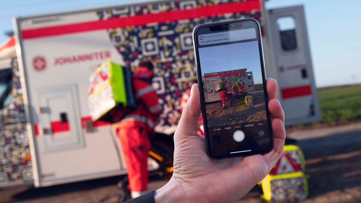 Symbolbild: In einer gestellten Szene der Johanniter-Unfall-Hilfe ist auf einem Smartphone der QR-Code auf einem Rettungswagen zu sehen, der die Botschaft «Gaffen tötet» enthält. (Quelle: dpa/A. Wagenzik)