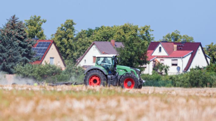 Symbolbild: Ein Landwirt fährt bei flimmernder Hitze mit Traktor und Sichelmulcher über ein abgeerntetes Getreidefeld. (Quelle: dpa/S. Stache)