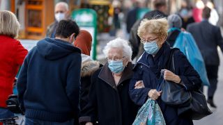 Symbolbild: Zwei ältere Damen tragen eine Mund-Nase-Schutzmaske und laufen mit Taschen durch eine Fußgängerzone. (Quelle: dpa/R. Oberhäuser)