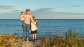 Eine Mutter steht mir ihren zwei Kindern am Ufer der Ostsee. (Quelle: dpa/Benjamin Nolte)