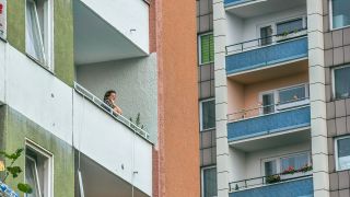 Eine Frau sitzt an ihrem Balkon in der Falkensee Chaussee, Berlin-Spandau (Bild: dpa/Schoening)