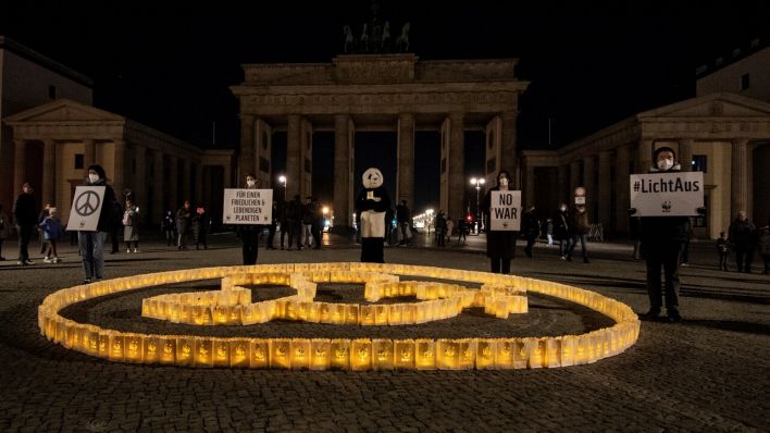 Vor dem Brandenburger Tor dessen Beleuchtung während der Earth Hour ausgeschaltet ist, stehen kleine Laternen, die in Form einer Friedenstaube aufgestellt wurden. (Quelle: dpa/Paul Zinken)