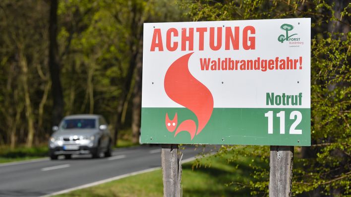 Ein Schild vom Landesbetrieb Forst Brandenburg mit der Aufschrift «Achtung Waldbrandgefahr! Notruf 112» steht an einer Landstraße in einem Wald. (Quelle: dpa/Patrick Pleul)