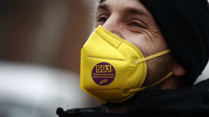 Ein Mann trägt eine Maske mit dem Logo der Initiative "Deutsche Wohnen und Co. enteignen" während einer Demonstration von einem Bündnis von Mieterinitiativen. (Quelle: dpa/Carsten Koall)