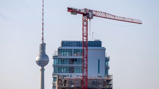 Ein Baukran arbeitet an einer Hochhaus-Baustelle vor der Kulisse des Berliner Fernsehturms. (Quelle: dpa/Monika Skolimowska)