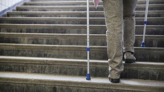 Symbolbild: Eine Frau benötigt Krücken zum Treppe steigen. Gestellte Szene vom 03.04.2015. (Quelle. dpa/Mascha Brichta)