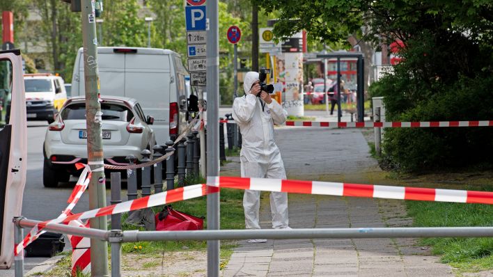 Ein Mitarbeiter der Spurensicherung dokumentiert am 29.04.2022 die Lage am Tatort in der Maximilianstraße, wo eine Frau auf offener Straße getötet worden ist. (Quelle: dpa/Paul Zinken)