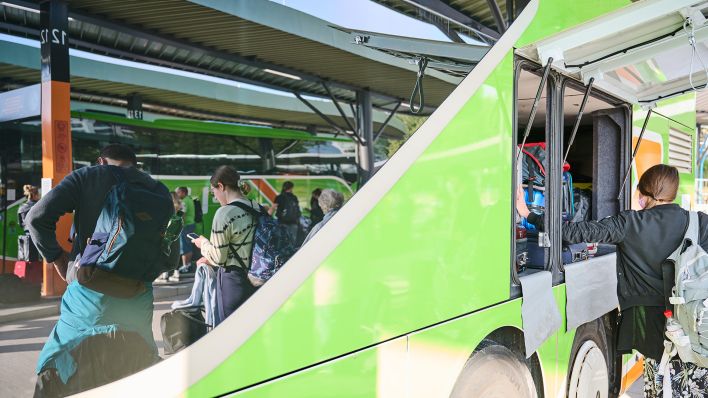 Eine Frau packt ihren Koffer in einen Flixbus während andere Menschen am Zentralen Omnibusbahnhof am Westkreuz warten. (Quelle: dpa/Annette Riedl)